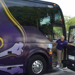 Image of one of the LLP trip bus driver's smiling from the doorway of the ECU Charter bus
